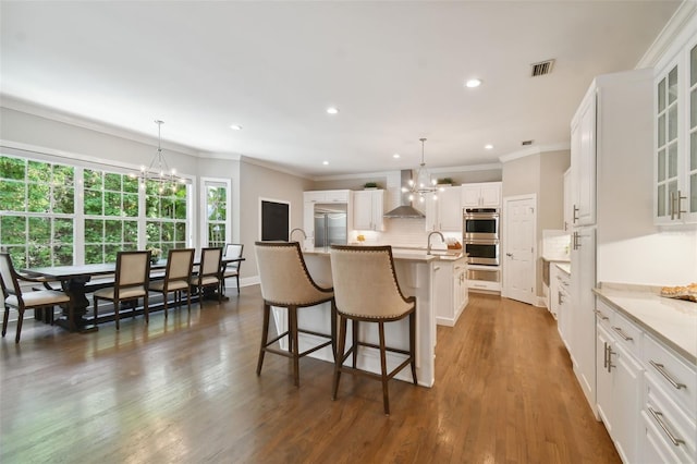 kitchen featuring decorative light fixtures, dark wood-type flooring, a notable chandelier, a kitchen island with sink, and appliances with stainless steel finishes