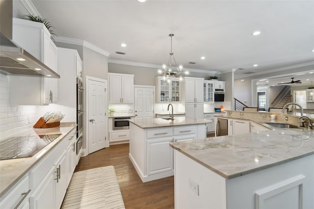 kitchen featuring wall chimney range hood, a center island with sink, dark hardwood / wood-style flooring, and backsplash