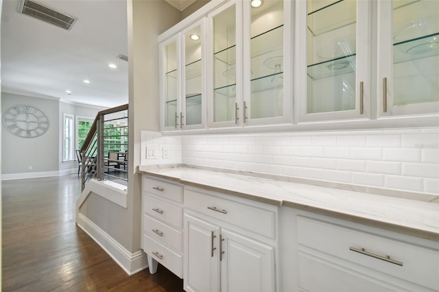 bar with dark hardwood / wood-style floors, crown molding, tasteful backsplash, light stone counters, and white cabinets