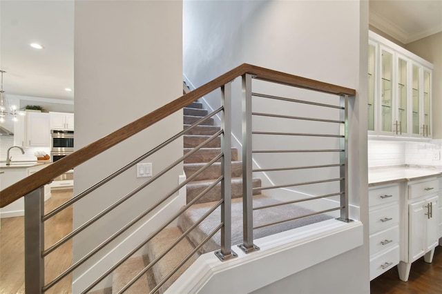 stairs with sink, ornamental molding, a chandelier, and dark hardwood / wood-style floors