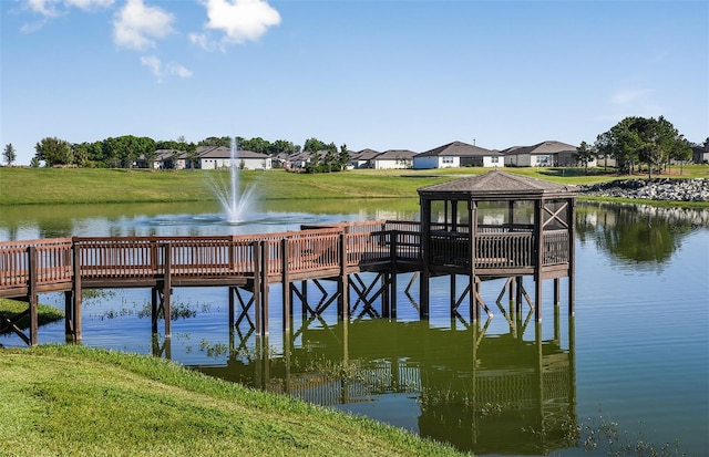 view of dock featuring a gazebo, a lawn, and a water view