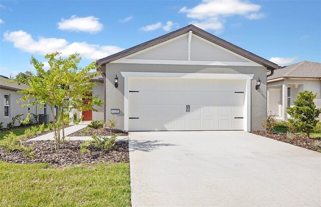 single story home with cooling unit and a garage