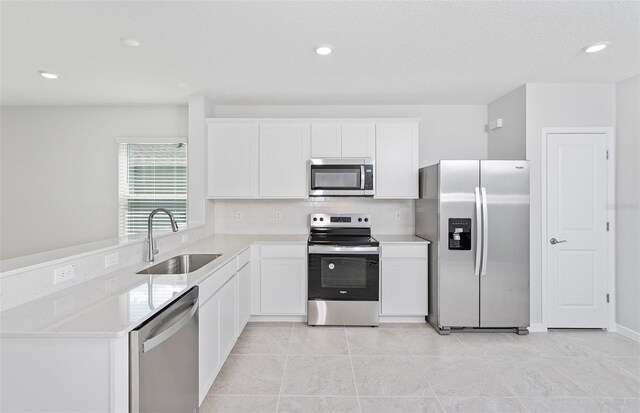 kitchen with light tile patterned floors, backsplash, appliances with stainless steel finishes, sink, and white cabinetry