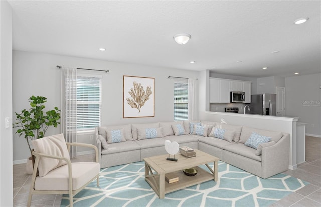 living room with a textured ceiling, sink, and light tile patterned flooring