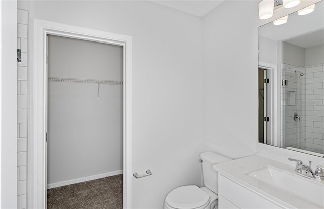 bathroom featuring tiled shower, vanity, and toilet