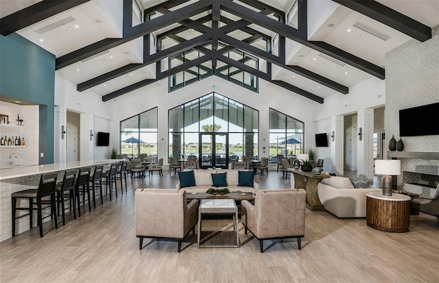 living room featuring high vaulted ceiling, wet bar, and light hardwood / wood-style flooring