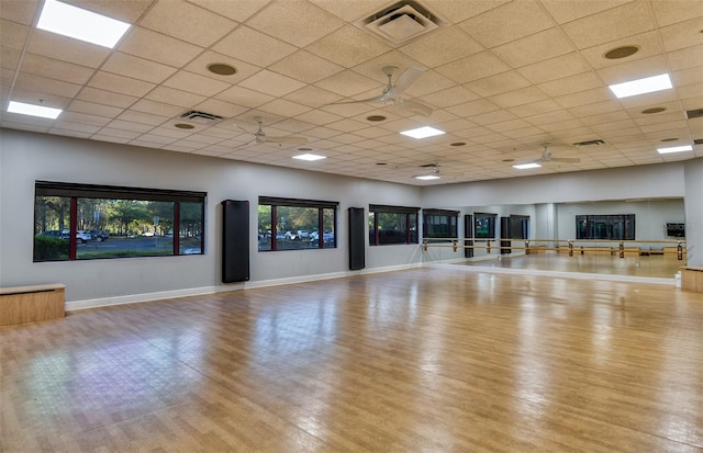 workout room with a drop ceiling, ceiling fan, and light hardwood / wood-style floors