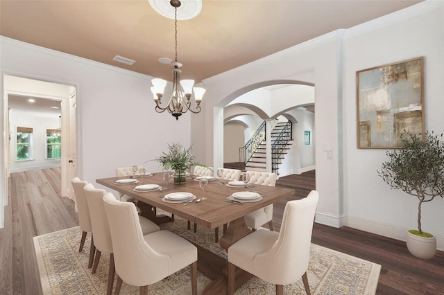 dining area with dark wood-type flooring, crown molding, and a chandelier