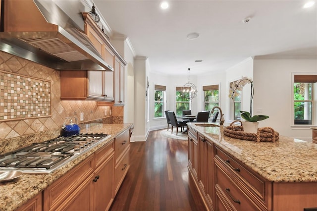 kitchen with sink, hanging light fixtures, range hood, a center island with sink, and stainless steel gas stovetop