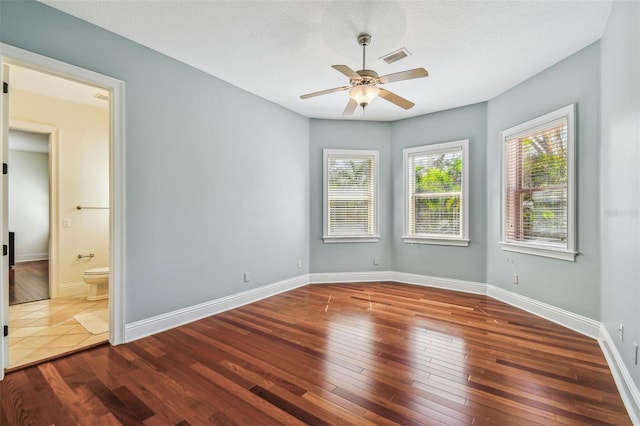 empty room featuring wood-type flooring, a textured ceiling, baseboards, and a ceiling fan