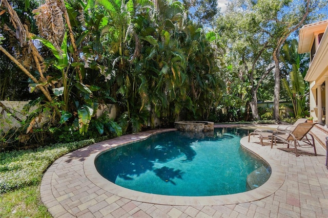 view of swimming pool with a pool with connected hot tub, fence, and a patio