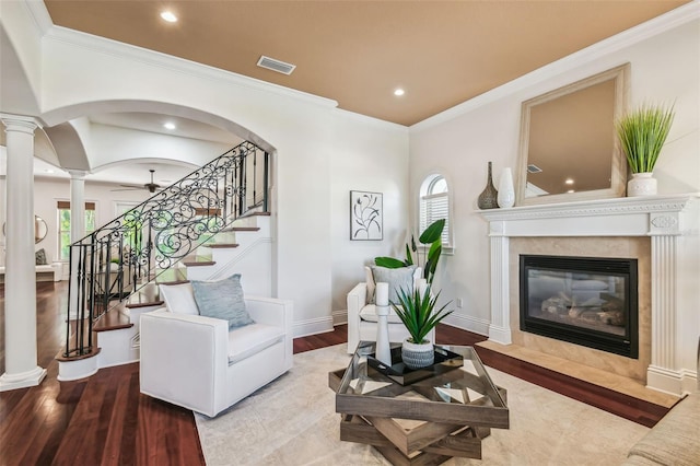 living room with wood finished floors, visible vents, baseboards, a glass covered fireplace, and ornate columns