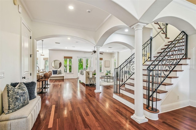 foyer entrance featuring ornamental molding, a ceiling fan, ornate columns, and wood finished floors