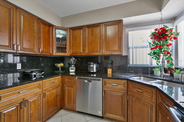 kitchen with dishwasher, dark stone countertops, light tile patterned floors, and backsplash