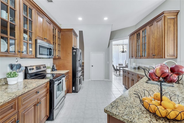 805 Woodcarver Ln, Brandon, FL 33510 - kitchen featuring appliances with stainless steel finishes, light stone countertops, brown cabinetry, and recessed lighting