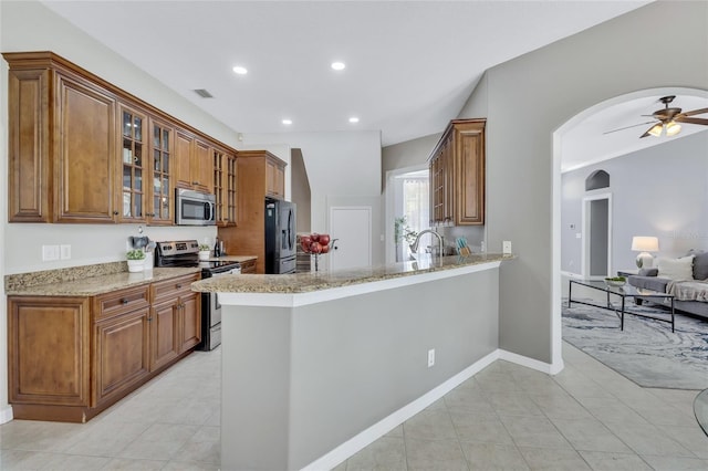 805 Woodcarver Ln, Brandon, FL 33510 - kitchen featuring appliances with stainless steel finishes, arched walkways, light tile patterned floors, brown cabinetry, and recessed lighting