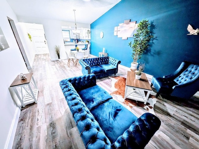 living room with an inviting chandelier, hardwood / wood-style flooring, and lofted ceiling