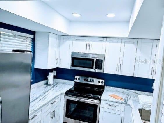 kitchen featuring white cabinetry, light stone counters, and stainless steel appliances