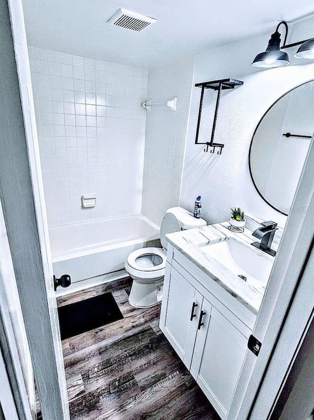 full bathroom featuring vanity, hardwood / wood-style flooring, toilet, and tiled shower / bath combo