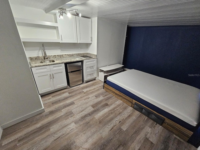 kitchen featuring sink, white cabinets, light stone countertops, and light hardwood / wood-style flooring