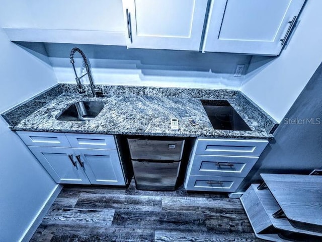 interior details with electric cooktop, sink, dark hardwood / wood-style floors, and dark stone countertops