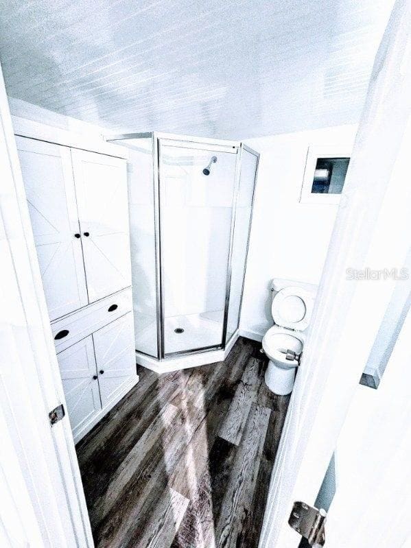 bathroom featuring an enclosed shower, toilet, and hardwood / wood-style floors