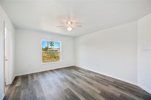 unfurnished room with a textured ceiling, dark wood-style flooring, a ceiling fan, and baseboards