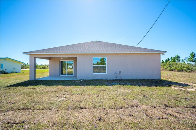 back of property featuring a patio area, roof with shingles, a yard, and stucco siding