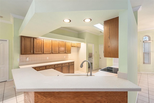 kitchen with kitchen peninsula, light tile patterned flooring, crown molding, and sink