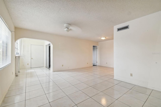 tiled empty room featuring a textured ceiling