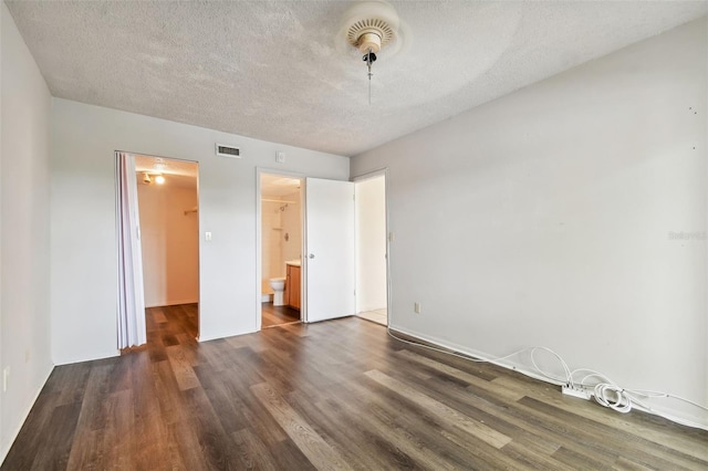 unfurnished bedroom featuring dark wood-type flooring, ceiling fan, a spacious closet, connected bathroom, and a closet