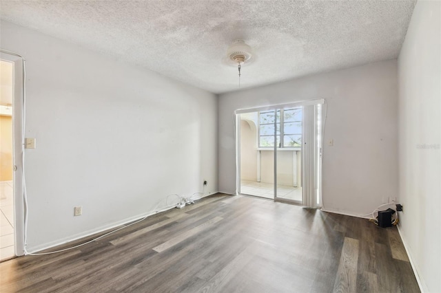 unfurnished room featuring dark wood-type flooring and a textured ceiling