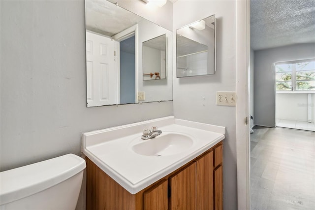 bathroom featuring vanity, a textured ceiling, and toilet