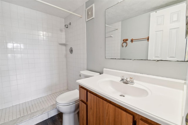 bathroom with vanity, toilet, and tiled shower