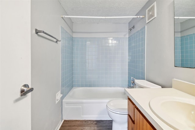 full bathroom featuring vanity, a textured ceiling, wood-type flooring, toilet, and tiled shower / bath