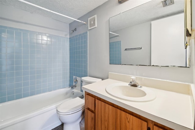 full bathroom featuring tiled shower / bath combo, toilet, a textured ceiling, and vanity