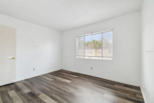 empty room featuring dark wood-type flooring and a textured ceiling