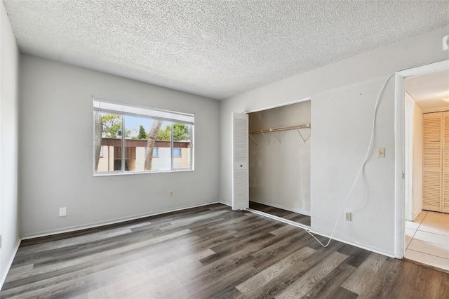 unfurnished bedroom featuring dark hardwood / wood-style flooring, a textured ceiling, and a closet