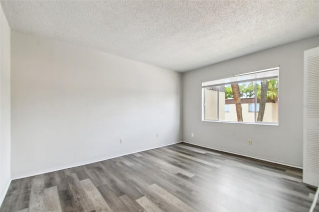 spare room featuring dark hardwood / wood-style floors and a textured ceiling