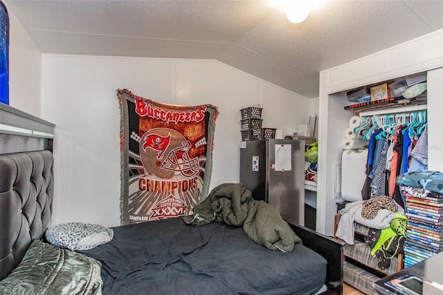 bedroom featuring lofted ceiling, a closet, and a textured ceiling