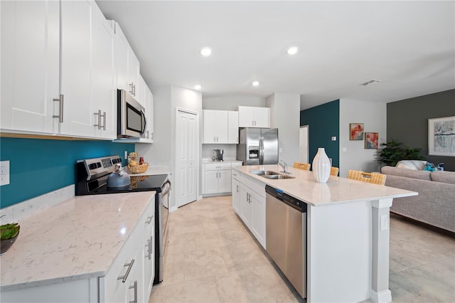 kitchen with white cabinetry, a kitchen island with sink, sink, and stainless steel appliances