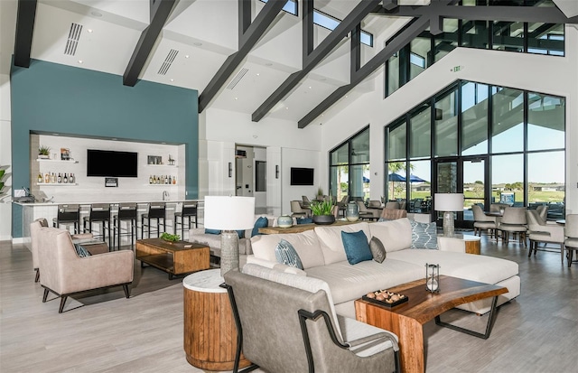 living room with beamed ceiling, bar, high vaulted ceiling, and light hardwood / wood-style floors