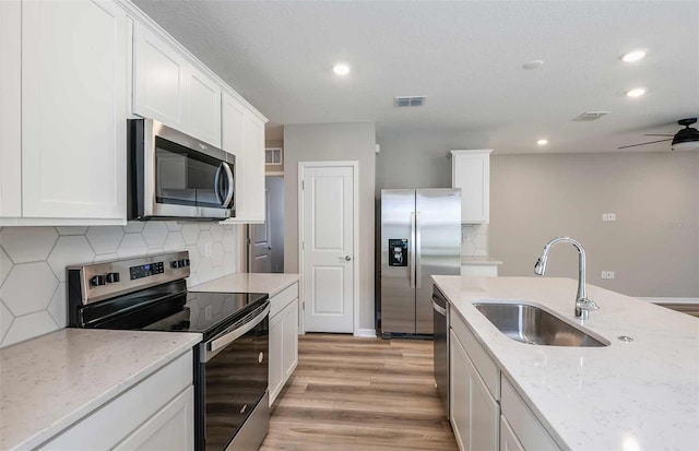 kitchen featuring white cabinetry, light stone countertops, light wood-type flooring, sink, and stainless steel appliances