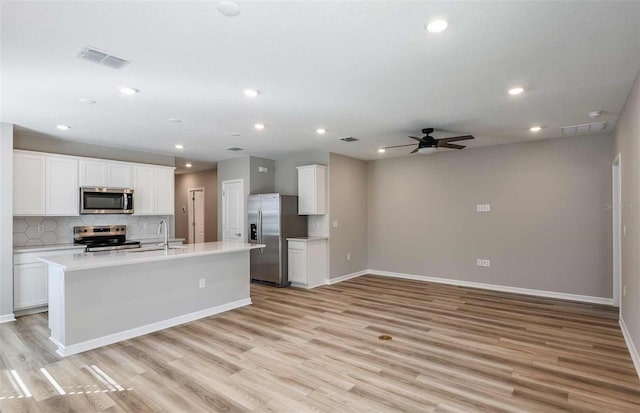 kitchen featuring light hardwood / wood-style floors, stainless steel appliances, a center island with sink, and white cabinets