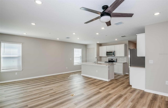 kitchen with ceiling fan, stainless steel appliances, white cabinets, decorative backsplash, and light hardwood / wood-style flooring