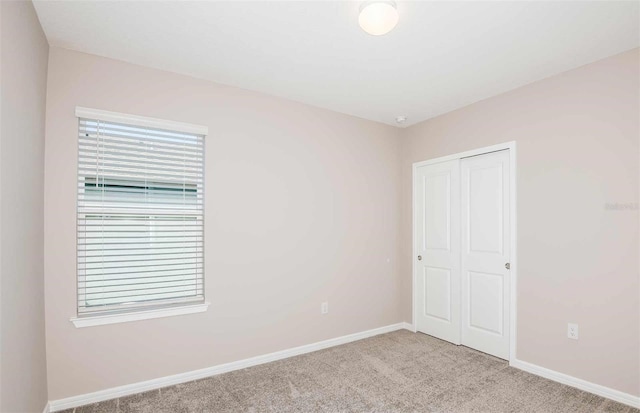 unfurnished bedroom featuring light carpet and a closet