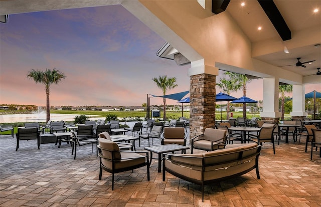 patio terrace at dusk featuring a water view and ceiling fan