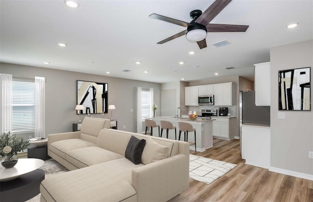 living room featuring a wealth of natural light, sink, light hardwood / wood-style flooring, and ceiling fan