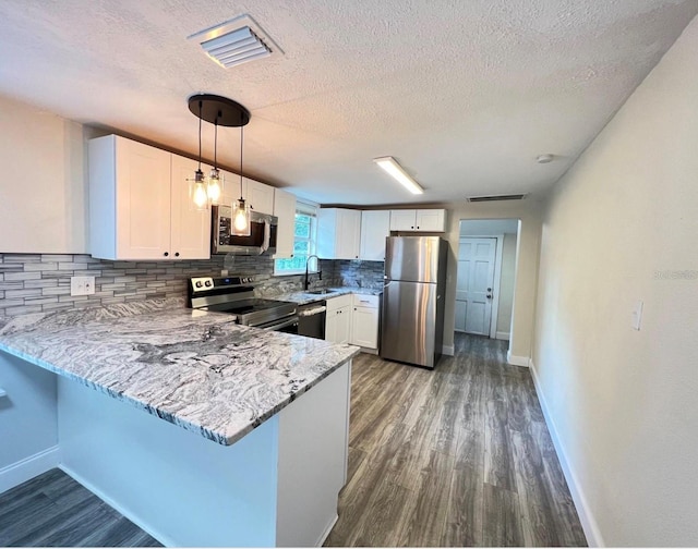 kitchen featuring appliances with stainless steel finishes, pendant lighting, white cabinets, and kitchen peninsula