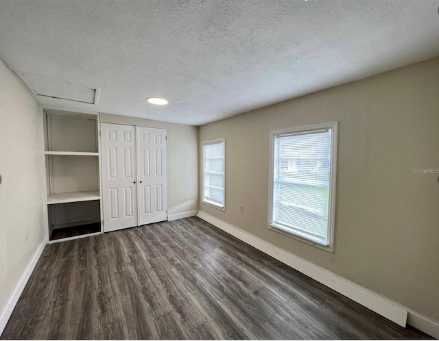 unfurnished bedroom with a closet, dark hardwood / wood-style floors, and a textured ceiling